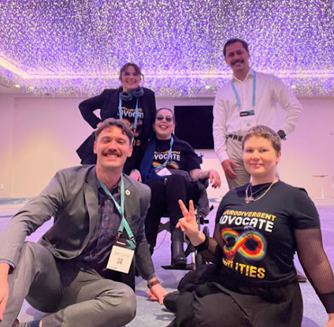 Disabled students smiling at the camera, one pulling a peace sign, another in a wheelchair with fairy lights above them